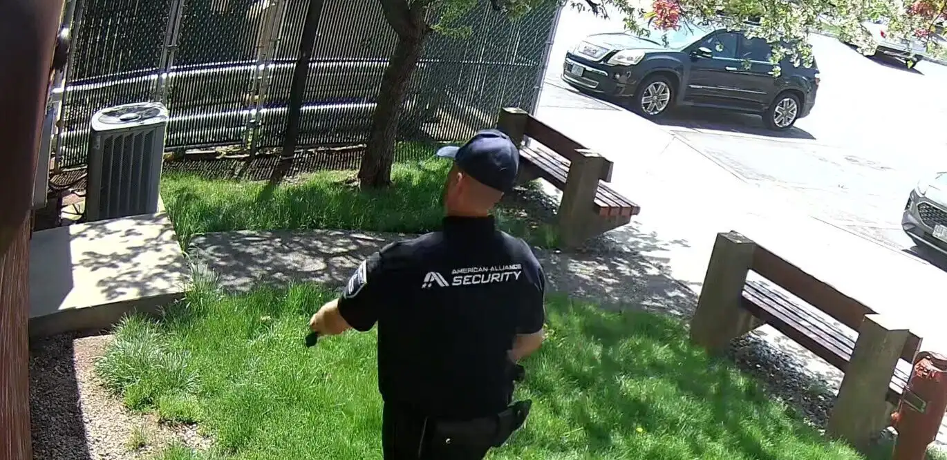 An American Alliance Security officer crossing the grounds of a property to check an area