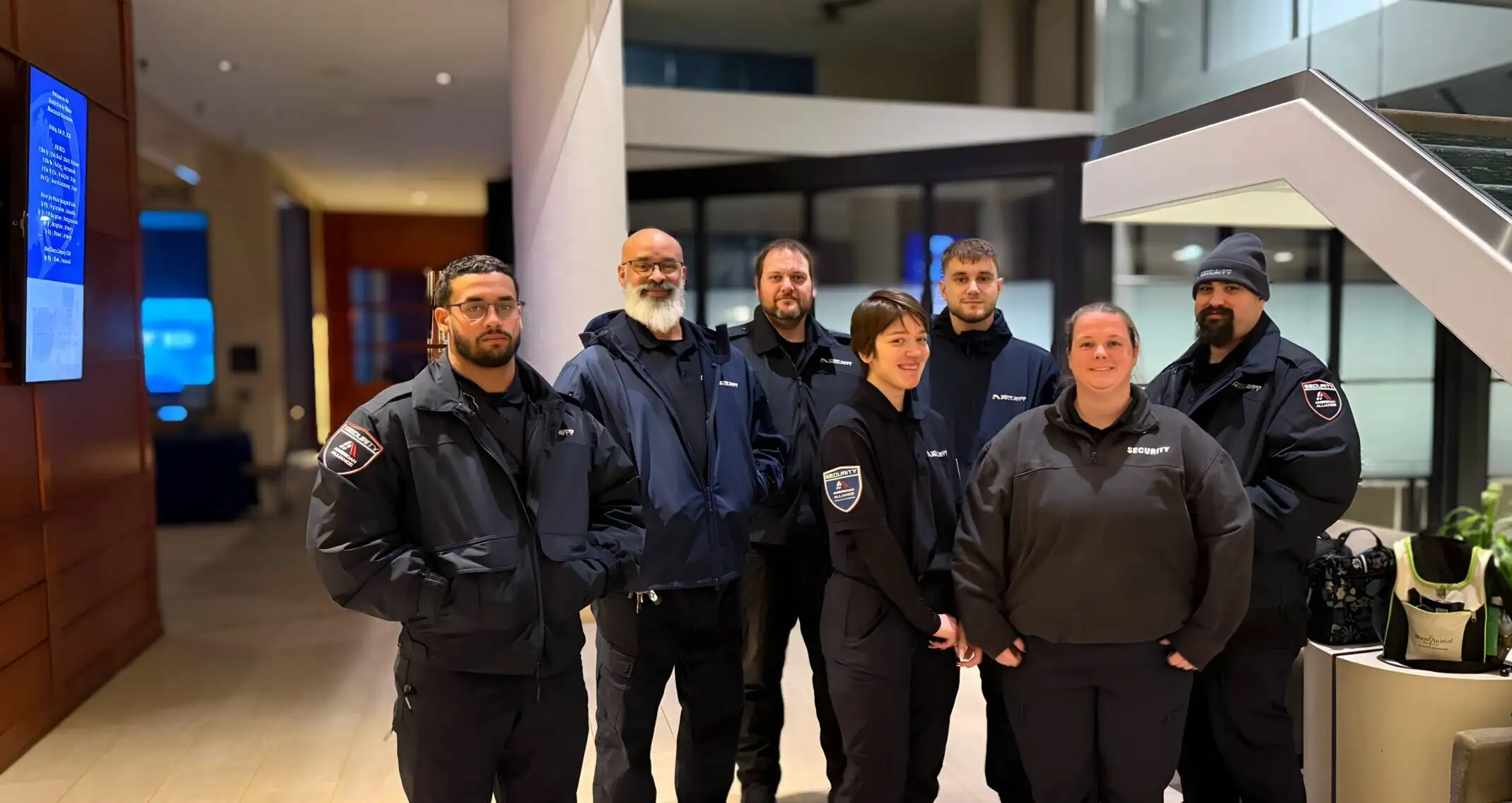 A team of seven American Alliance Security officers in uniform standing together in a hotel lobby