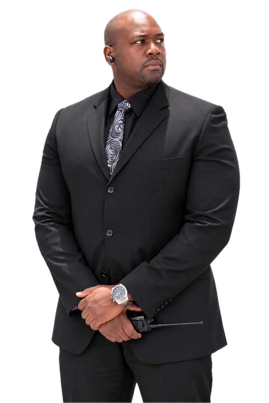 An executive protection agent in a dark suit with an earpiece and radio standing watch
