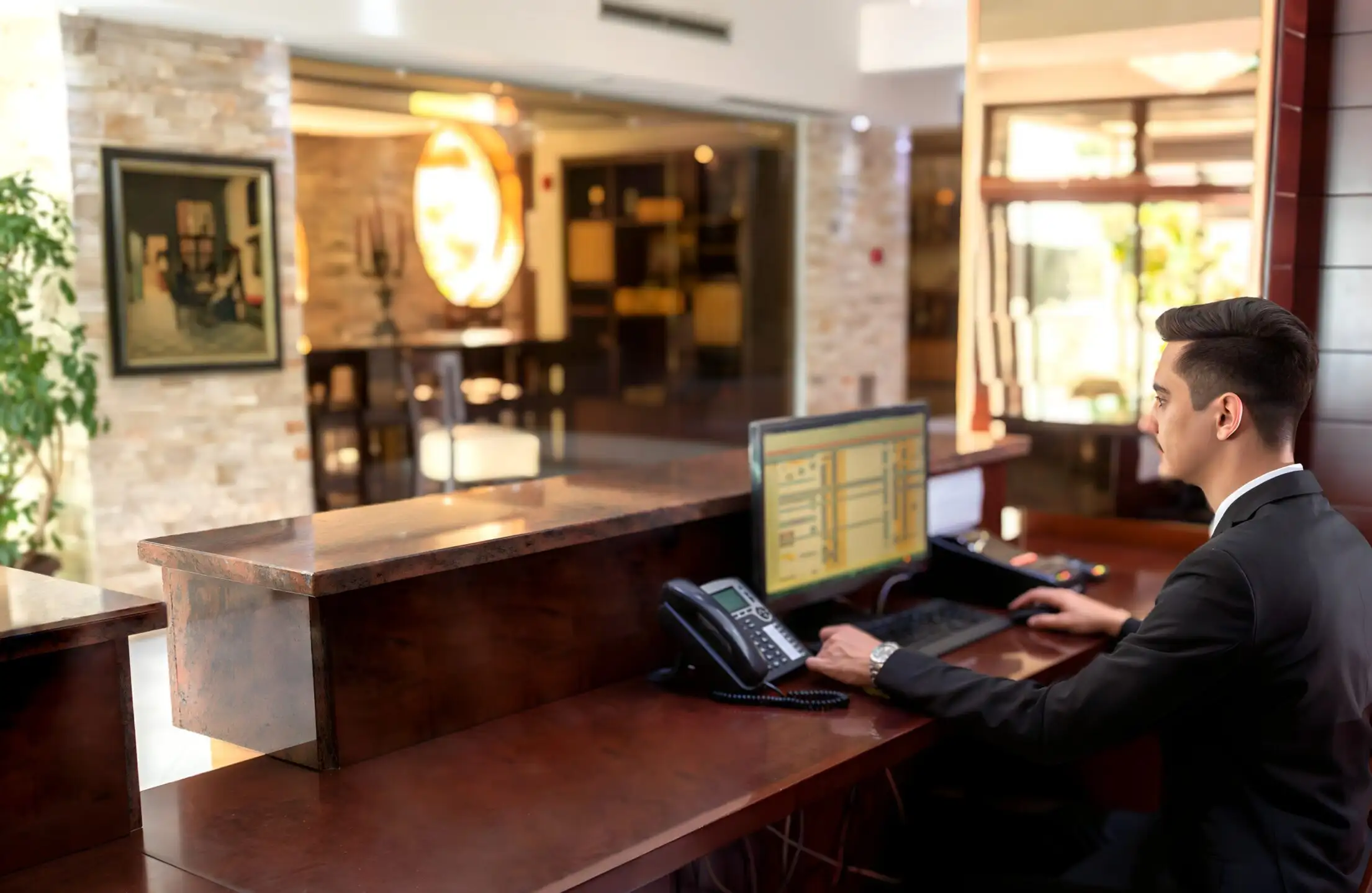 A front desk officer in a suit working at a hotel reception computer