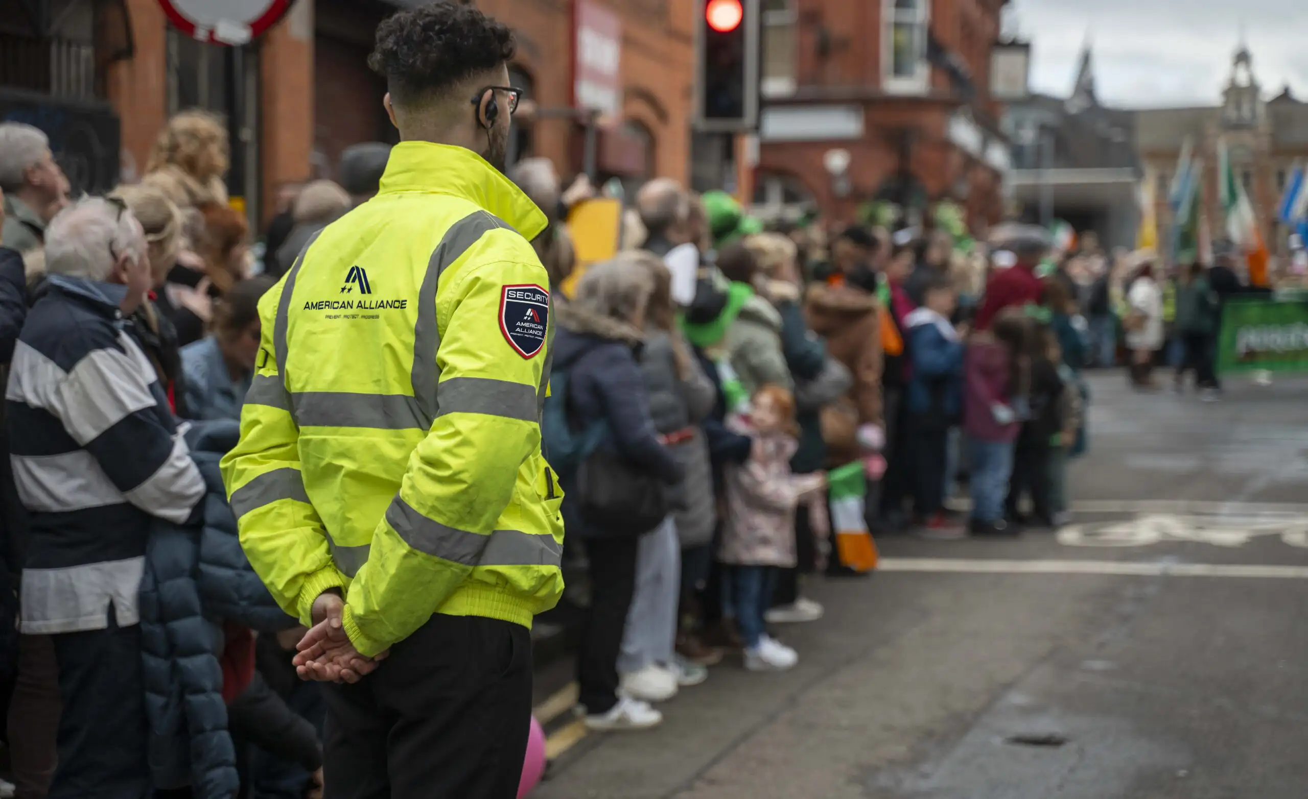American Alliance Security officer in a high-visibility jacket monitoring a crowd at an outdoor event