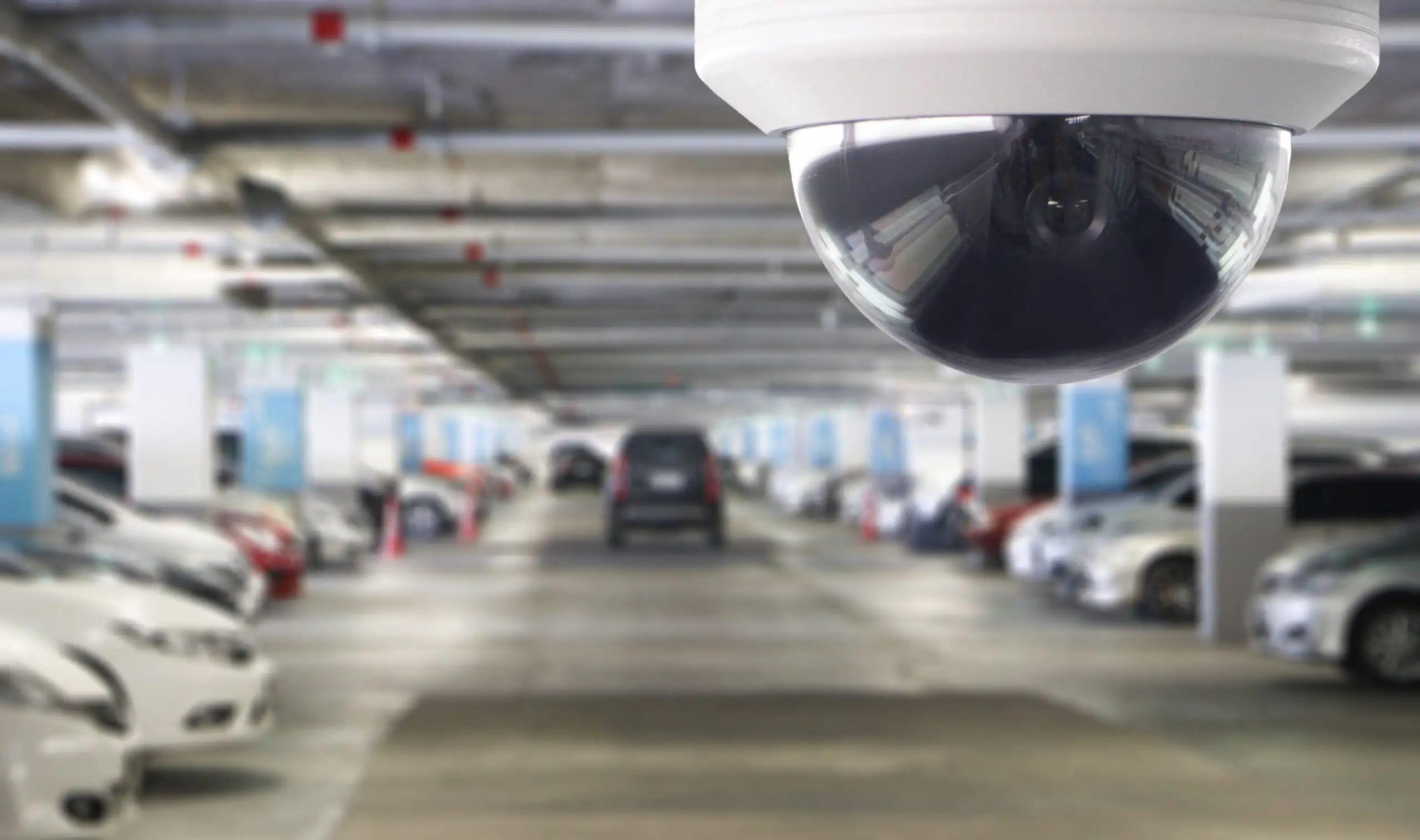 A dome security camera mounted over a parking garage